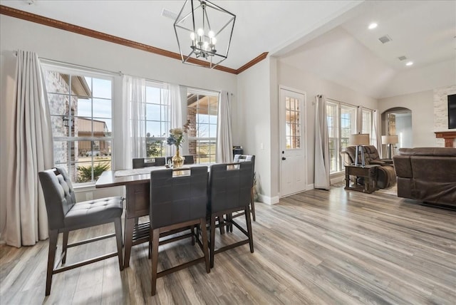 dining space with an inviting chandelier, light hardwood / wood-style flooring, ornamental molding, and vaulted ceiling