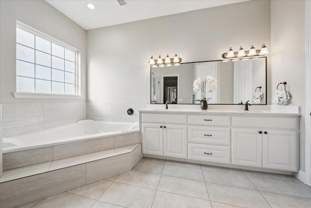 bathroom with tile patterned flooring, tiled tub, and vanity