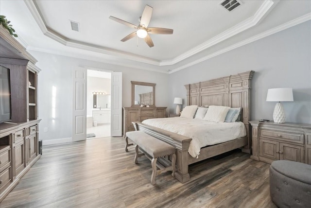 bedroom featuring a raised ceiling, wood finished floors, and visible vents