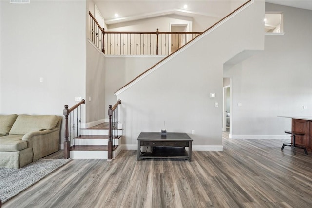 staircase with wood-type flooring and a high ceiling