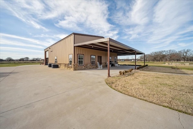 exterior space with central air condition unit, a carport, and driveway