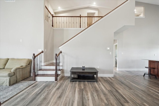 living area with stairs, wood finished floors, baseboards, high vaulted ceiling, and recessed lighting