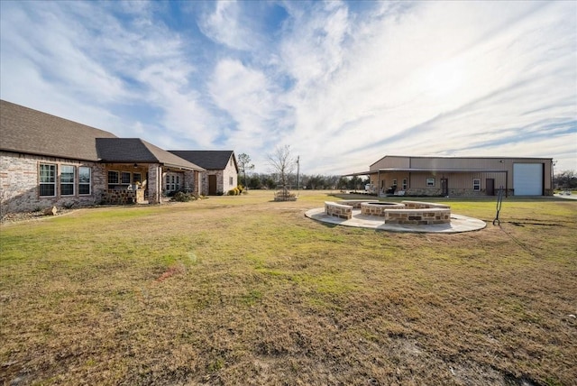 view of yard featuring a garage and an outdoor fire pit