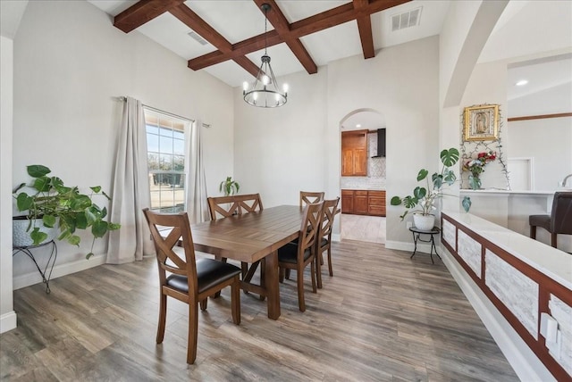 dining space featuring an inviting chandelier, baseboards, wood finished floors, beamed ceiling, and coffered ceiling