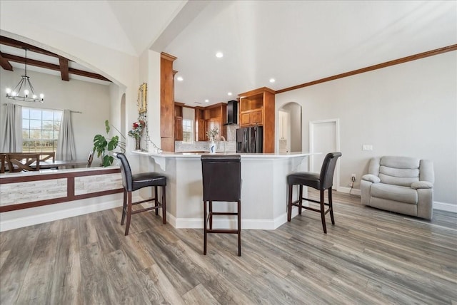 kitchen with a kitchen bar, beam ceiling, kitchen peninsula, and refrigerator with ice dispenser