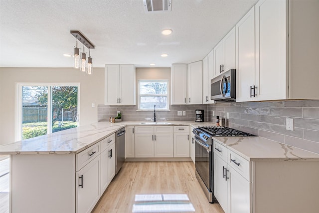 kitchen featuring appliances with stainless steel finishes, kitchen peninsula, sink, and white cabinets