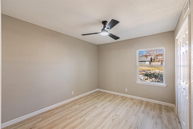 unfurnished room with ceiling fan, a textured ceiling, and light wood-type flooring