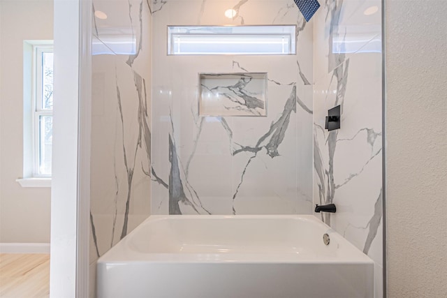 bathroom with hardwood / wood-style floors, a wealth of natural light, and bathtub / shower combination