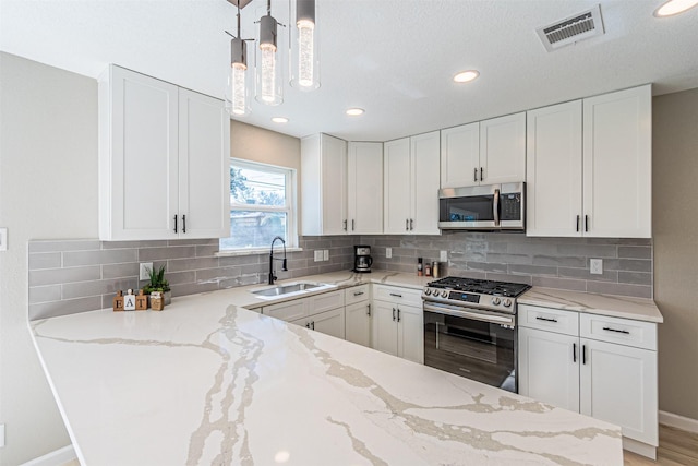 kitchen featuring sink, decorative light fixtures, white cabinets, and appliances with stainless steel finishes