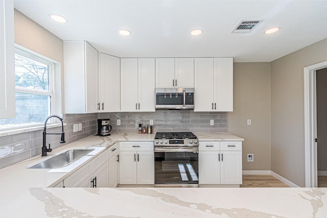 kitchen with appliances with stainless steel finishes, sink, and white cabinets