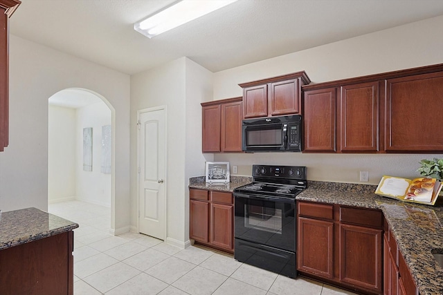 kitchen featuring dark stone countertops, light tile patterned floors, and black appliances