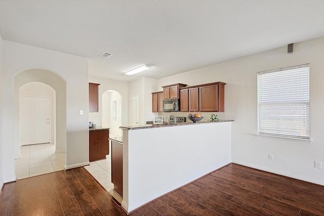 kitchen with hardwood / wood-style floors, light stone countertops, and kitchen peninsula