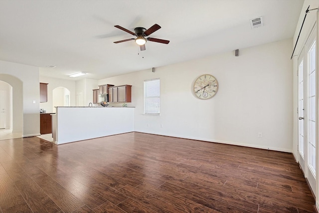 unfurnished living room with dark hardwood / wood-style flooring and ceiling fan