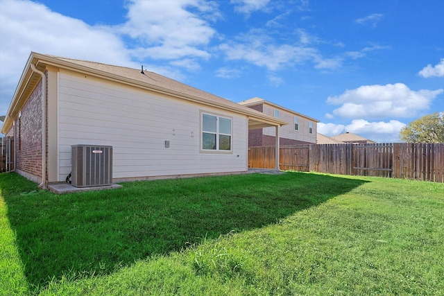 rear view of property with central AC and a yard