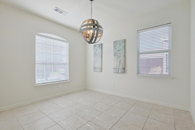 tiled empty room featuring a chandelier