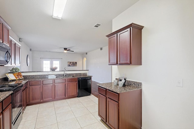 kitchen with sink, dark stone counters, light tile patterned floors, ceiling fan, and black appliances