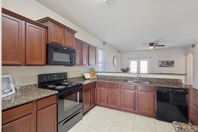 kitchen featuring sink, dark stone counters, light tile patterned floors, ceiling fan, and black appliances