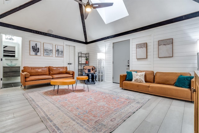 living room with wood-type flooring, high vaulted ceiling, ceiling fan, and a skylight