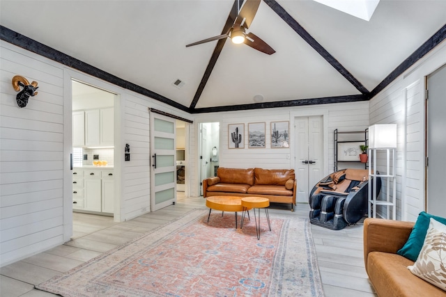 living room with beamed ceiling, ceiling fan, wooden walls, and a skylight