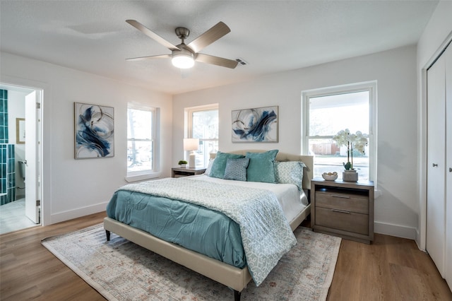 bedroom featuring multiple windows, light wood-type flooring, ceiling fan, and a closet