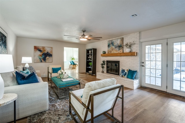 living room featuring hardwood / wood-style flooring, a brick fireplace, and ceiling fan