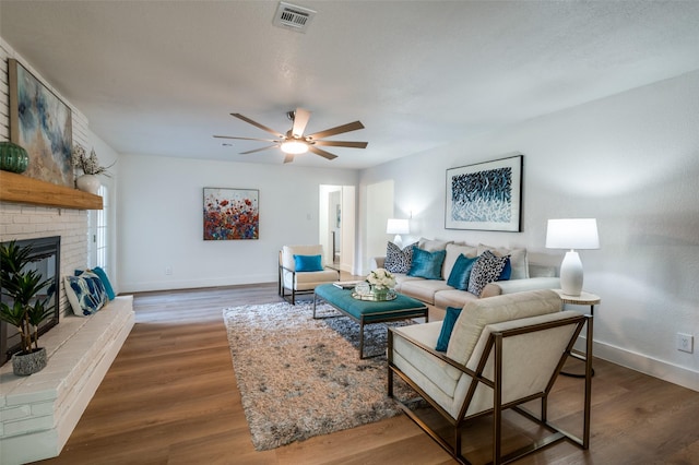 living room featuring wood-type flooring, ceiling fan, and a fireplace