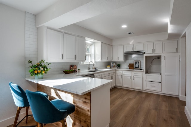 kitchen with white cabinetry, backsplash, sink, and kitchen peninsula