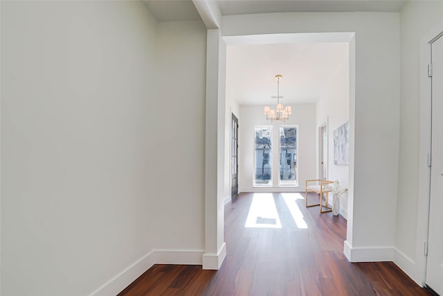 hallway with dark hardwood / wood-style floors and a chandelier