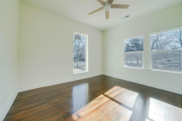 unfurnished room featuring ceiling fan, dark wood-type flooring, visible vents, and baseboards