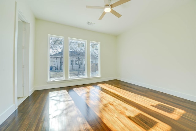 unfurnished room featuring dark wood-style floors, ceiling fan, visible vents, and baseboards