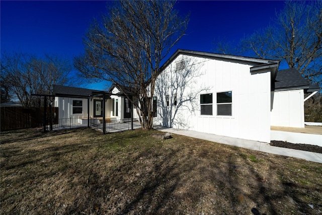 exterior space featuring fence, a front lawn, and board and batten siding