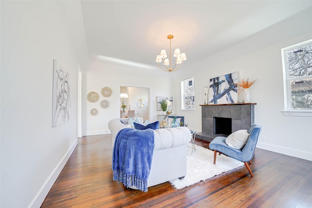 living room with a tiled fireplace, dark hardwood / wood-style floors, and a chandelier