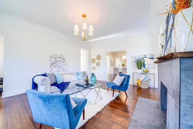 living area with wood-type flooring, a notable chandelier, and baseboards