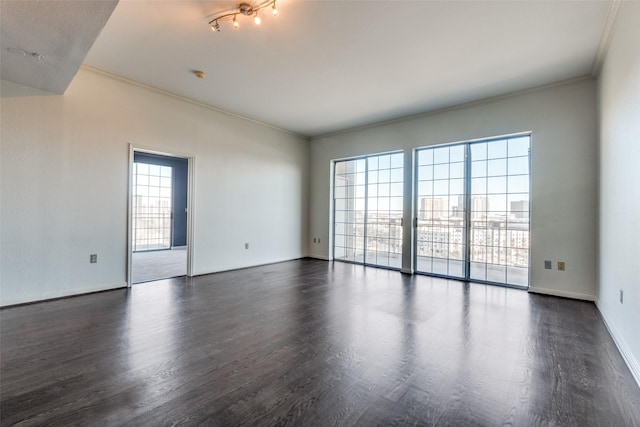 empty room with ornamental molding, a healthy amount of sunlight, and dark hardwood / wood-style flooring