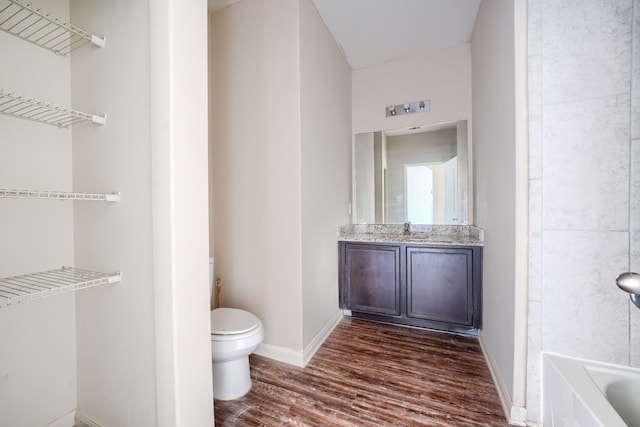 bathroom featuring vanity, hardwood / wood-style floors, toilet, and a bathing tub