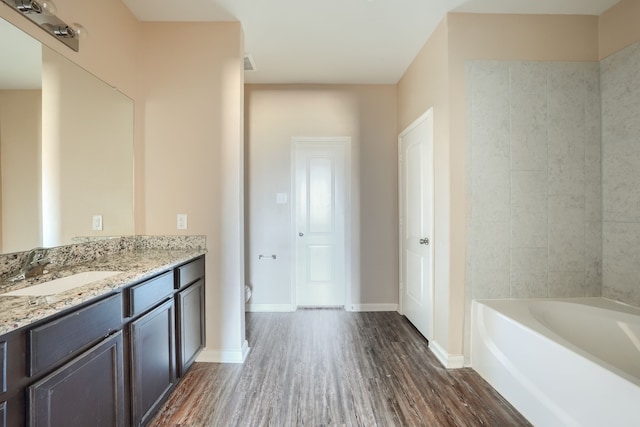 bathroom featuring hardwood / wood-style flooring, vanity, a bathing tub, and toilet