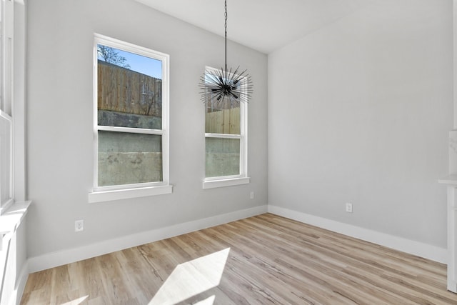 unfurnished dining area featuring an inviting chandelier and light hardwood / wood-style flooring