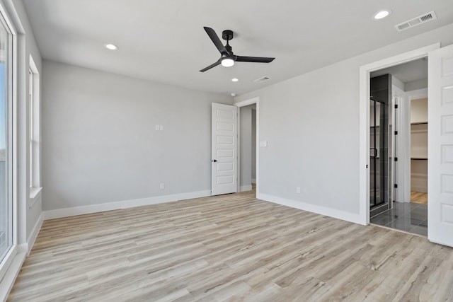 unfurnished bedroom with multiple windows, connected bathroom, ceiling fan, and light hardwood / wood-style floors