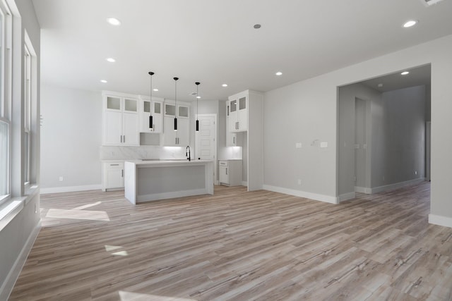 kitchen featuring decorative light fixtures, light hardwood / wood-style floors, a kitchen island, and white cabinets