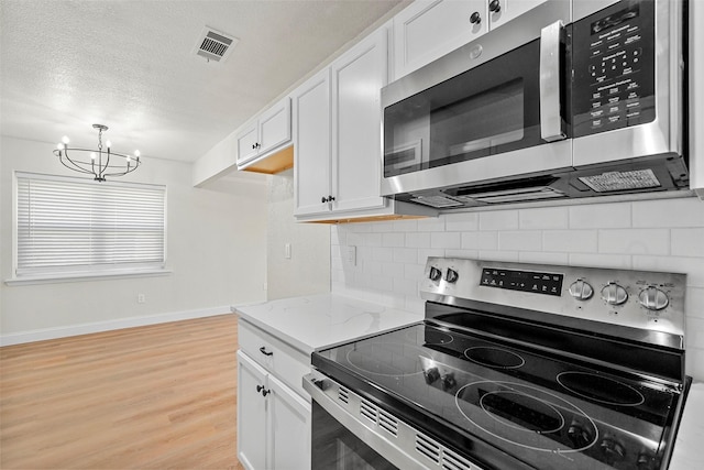 kitchen featuring light stone counters, stainless steel appliances, light hardwood / wood-style floors, decorative backsplash, and white cabinets