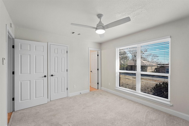 unfurnished bedroom with ceiling fan, light colored carpet, and a closet