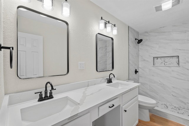 bathroom with vanity, tiled shower, hardwood / wood-style floors, and toilet