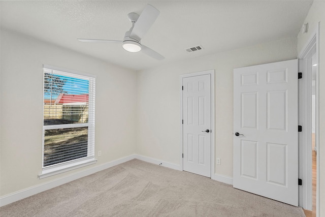 unfurnished bedroom with light colored carpet, ceiling fan, and a closet