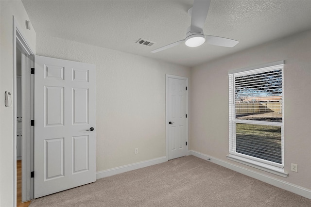 empty room with light carpet, a textured ceiling, and ceiling fan