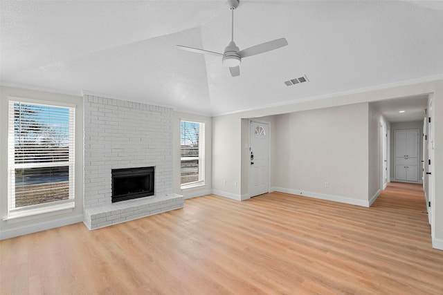 unfurnished living room featuring a fireplace, lofted ceiling, ceiling fan, plenty of natural light, and light wood-type flooring