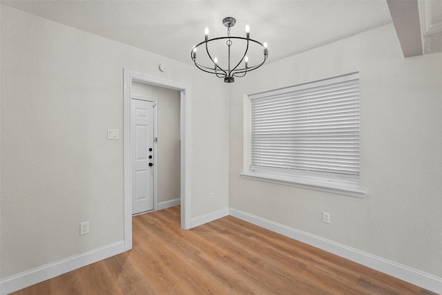 unfurnished room with an inviting chandelier and light hardwood / wood-style flooring