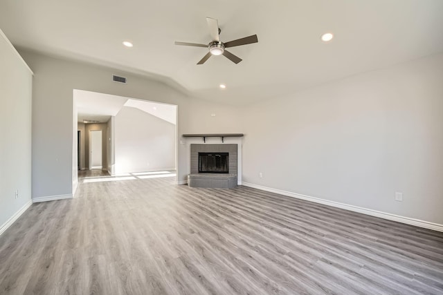 unfurnished living room with vaulted ceiling, ceiling fan, a fireplace, and light hardwood / wood-style floors