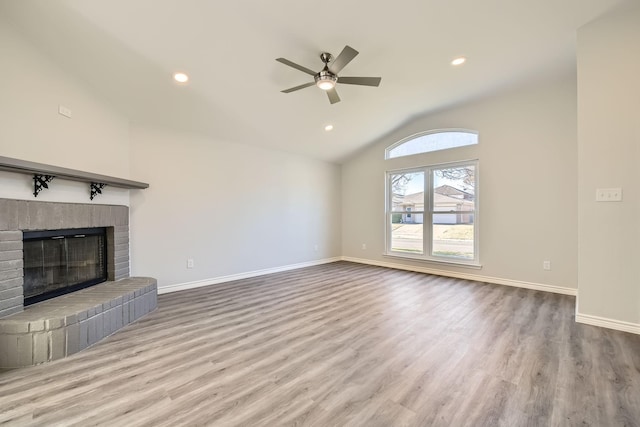 unfurnished living room with light wood-type flooring, a fireplace, ceiling fan, and vaulted ceiling