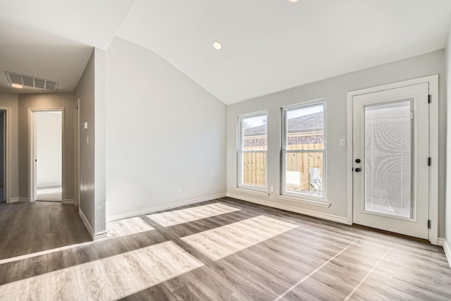 empty room with light hardwood / wood-style floors and vaulted ceiling