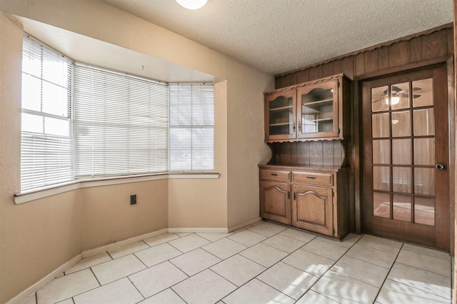 unfurnished dining area featuring a textured ceiling and light tile patterned floors